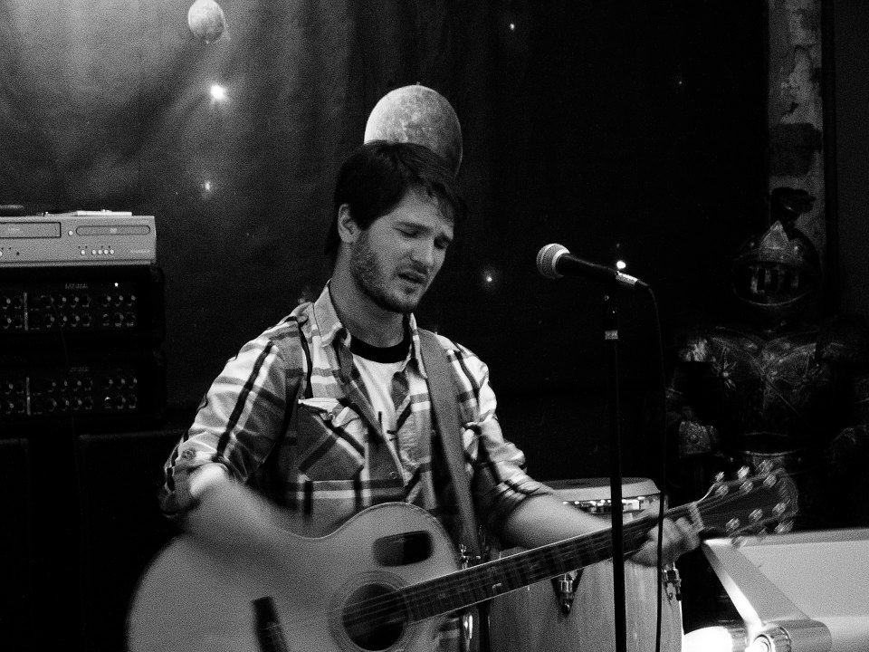 Black-and-white shot of Chris Ulery singing while playing acoustic guitar