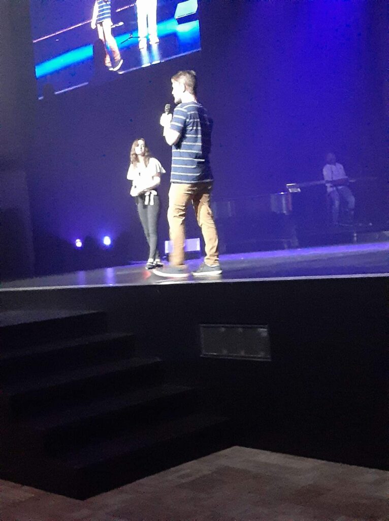 Chris and Jessica Ulery speaking together on a wide stage with screens overhead