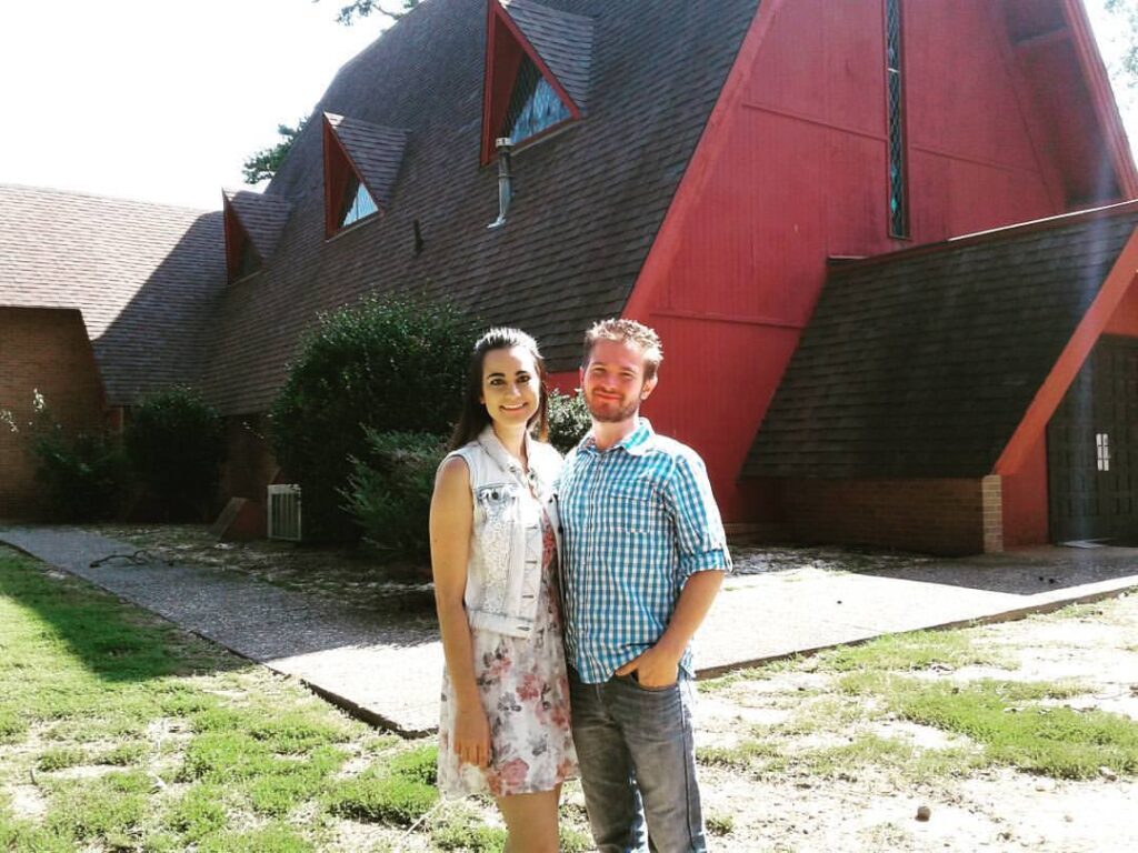Chris and Jessica Ulery standing together outside a red A-frame church building