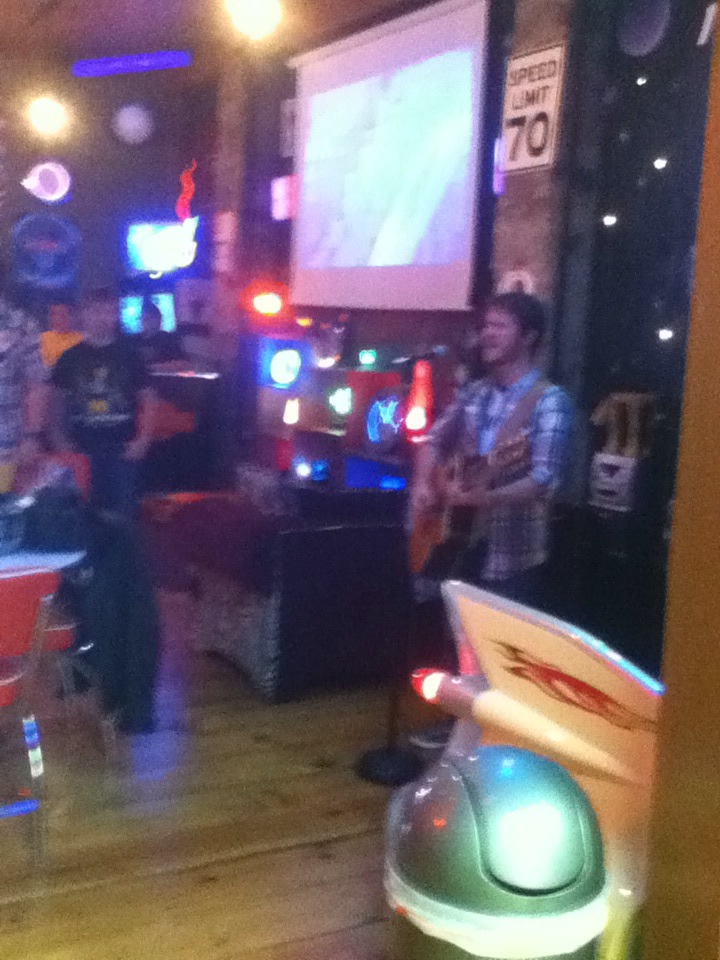 Chris Ulery leading worship with guitar in a neon-lit youth hangout