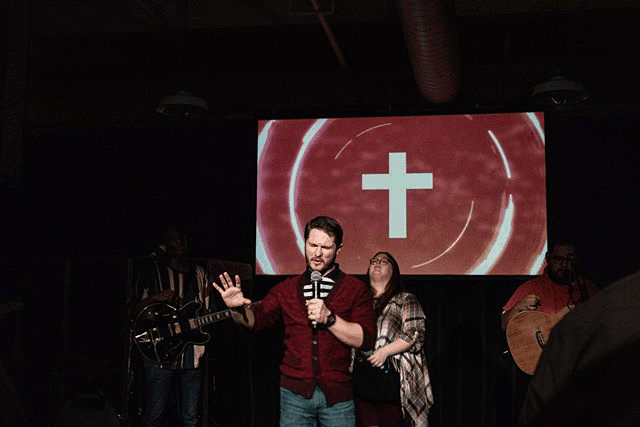 Chris Ulery preaching in front of a cross on the screen at Victory Downtown
