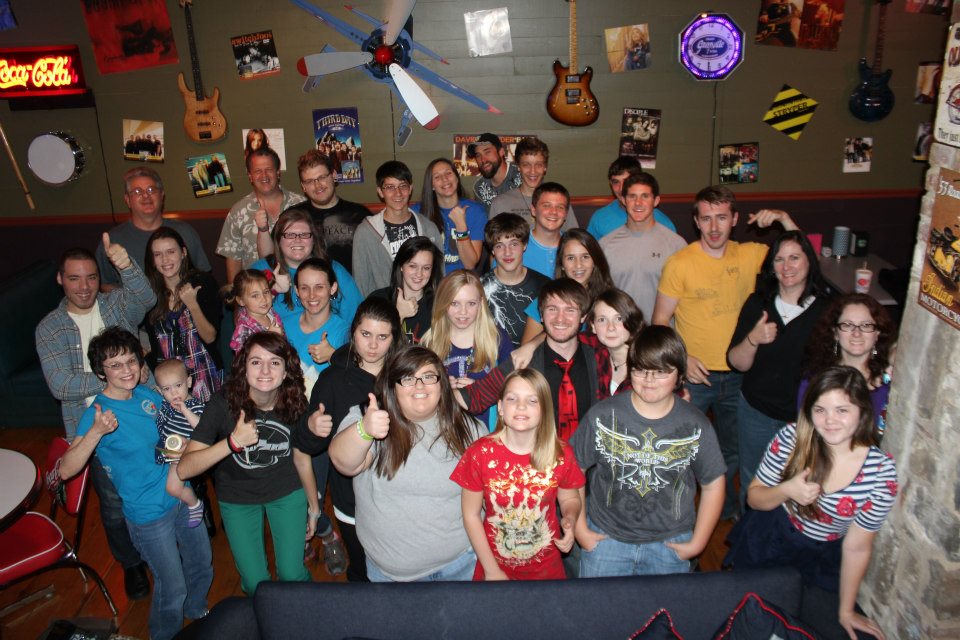 Smiling youth group giving thumbs up in a decorated room at a Chris Ulery event