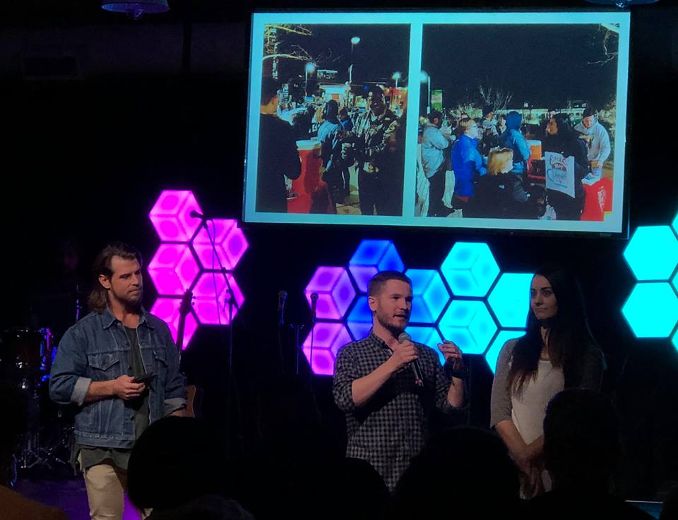 Chris Ulery speaking in a plaid shirt with colorful hexagon lights behind