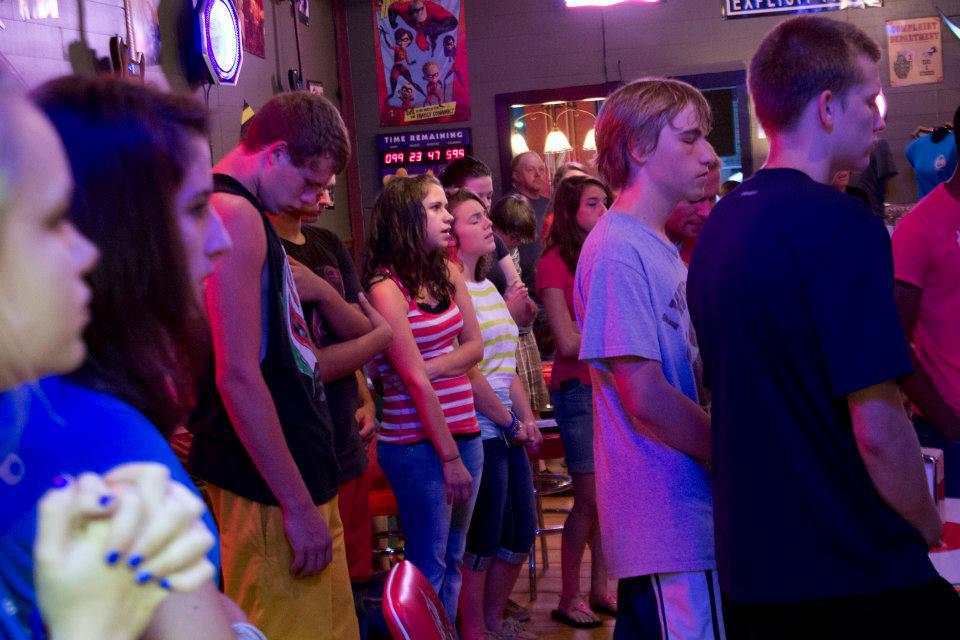Teens standing in worship under colorful lights at a Chris Ulery youth night