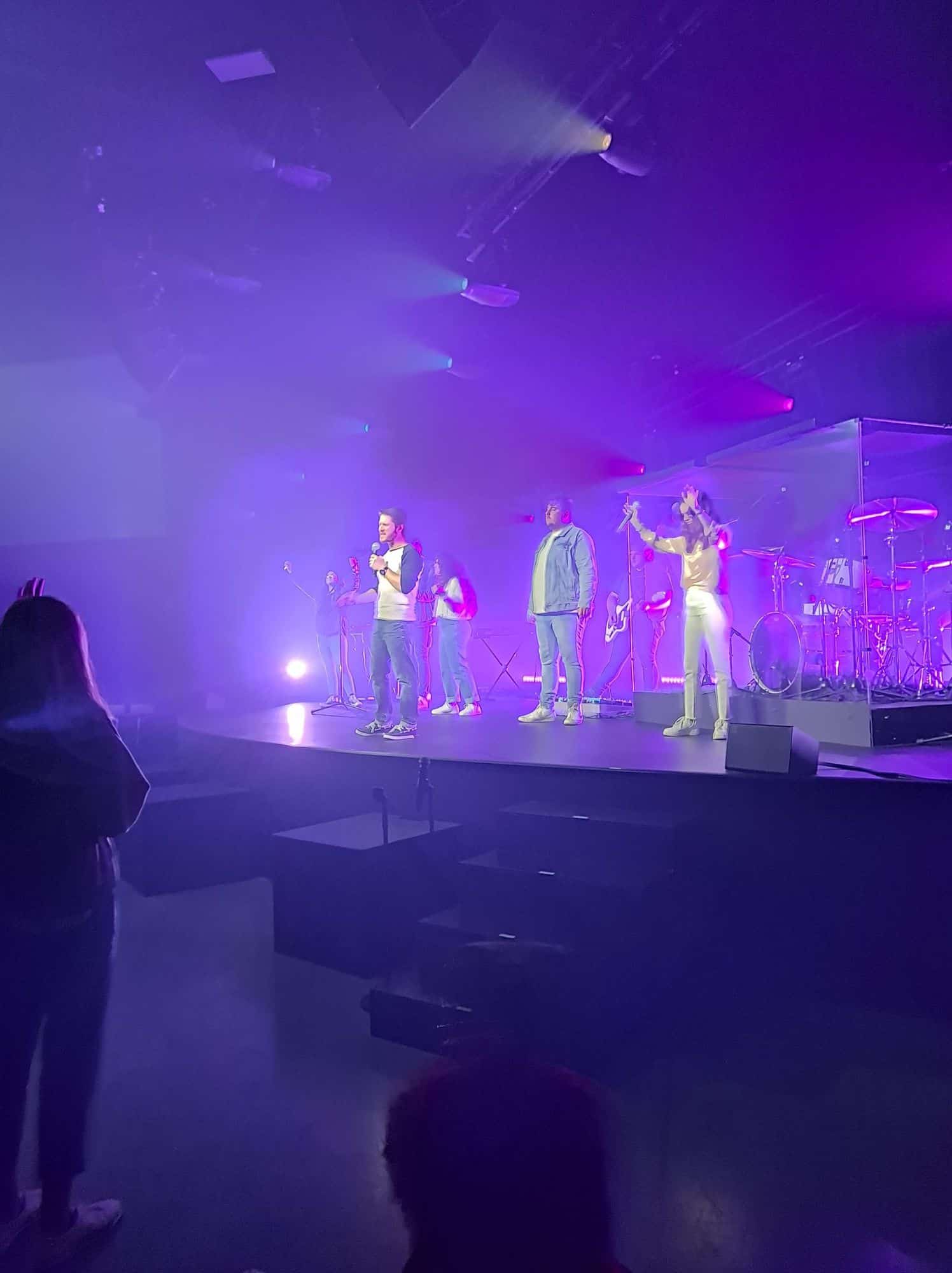 Chris Ulery leading a youth night with a worship team under purple stage lights
