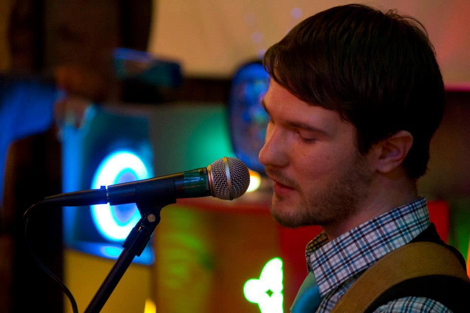 Close-up of Chris Ulery singing into a microphone under colorful lights