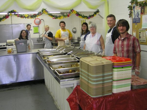 Volunteers serving meals in a decorated church kitchen
