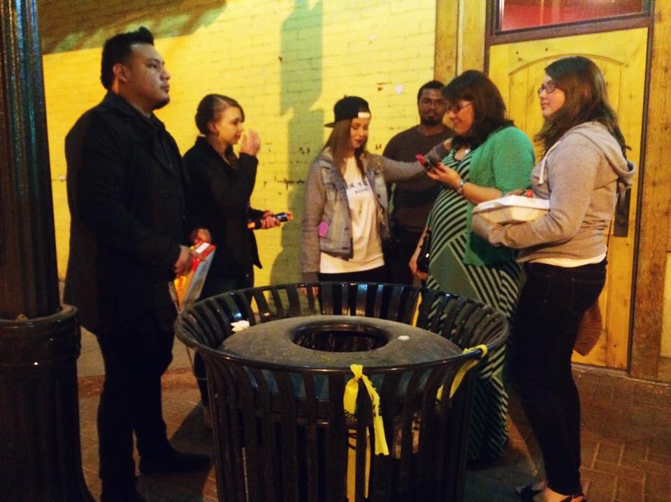 Outreach volunteers praying with people on a downtown sidewalk at night